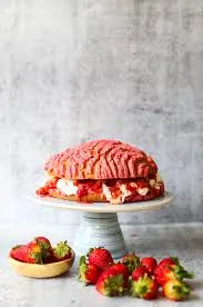 Strawberry concha cake on a white cake stand showing the full layered height